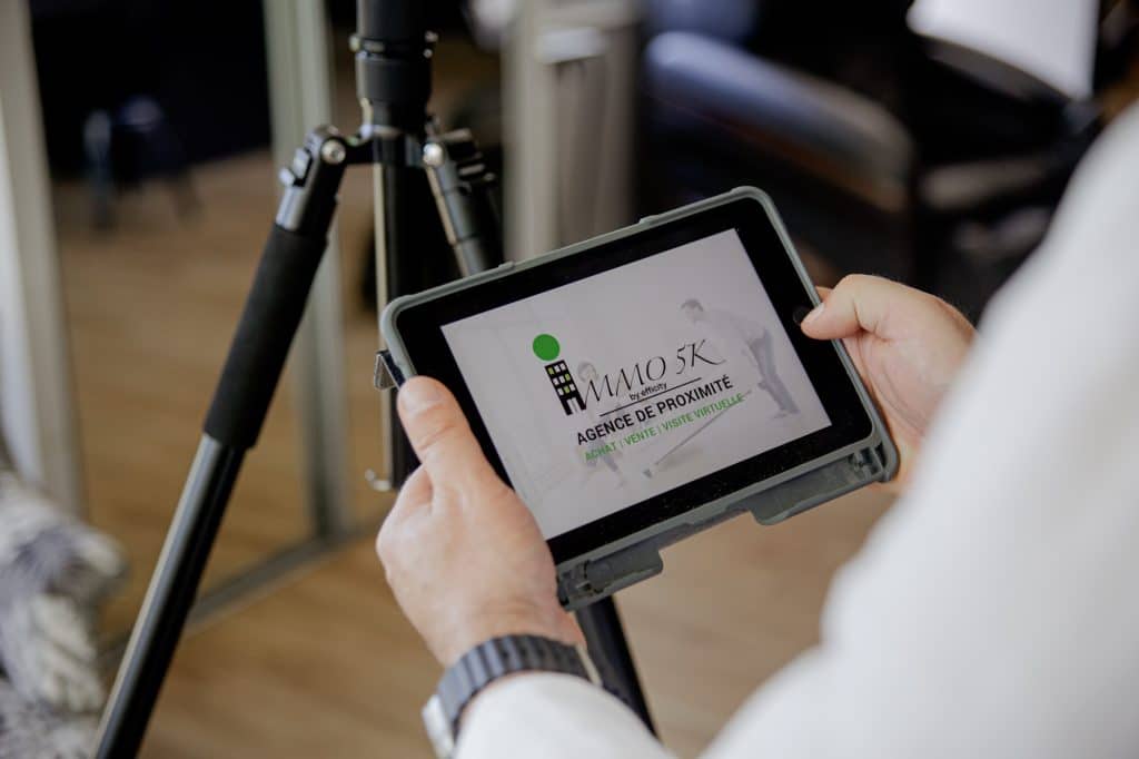 gros plan sur les mains de votre agent immobilier préféré à Rillieux la pape qui tiennent un iPad sur lequel on peut voir le logo Immo5k by efficity.