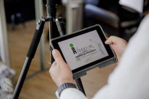 gros plan sur les mains de votre agent immobilier préféré à Rillieux la pape qui tiennent un iPad sur lequel on peut voir le logo Immo5k by efficity.